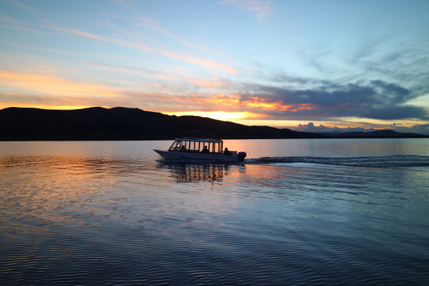 silhouette-cruising-boat-lake-titicaca-sunset-puno-peru_76000-705